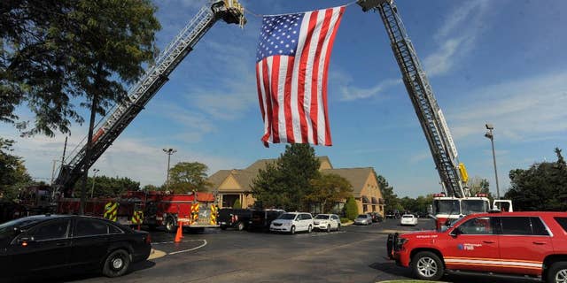 A large American flag is unfurled by Sterling Heights and Washington Twp. Fire Departments as mourners begin to arrive for visitation for Detroit Police officer Ken Steil in Sterling Heights, Mich., Wednesday Sept. 21, 2016. Steil died unexpectedly Saturday of a blood clot, five days after being shot in the shoulder. (Steve Perez/Detroit News via AP)
