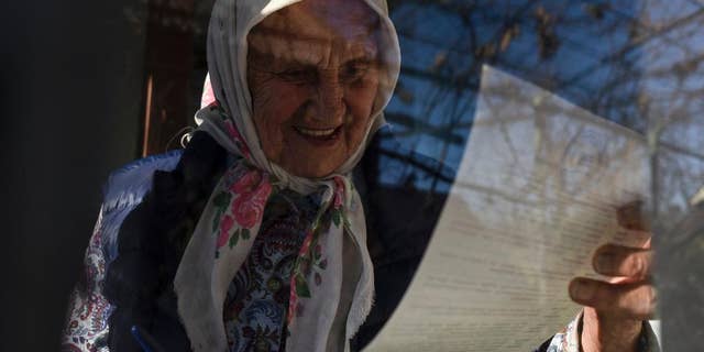 An elderly Ukrainian woman reads a ballot paper in her house during parliamentary elections in the town of Konstantinovka, Donetsk region eastern Ukraine, Sunday, Oct. 26, 2014. Voters in Ukraine headed to the polls Sunday to elect a new parliament. (AP Photo/Evgeniy Maloletka)