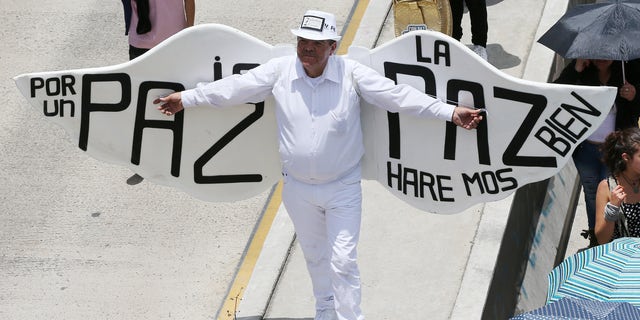 A man, wearing angel wings, with a message that reads in Spanish; "Peace will be good for the country," takes part in a march for peace on the National Day of Memory and Solidarity with Victims of the Armed Conflict, in Bogota, Colombia, Thursday, April 9, 2015. Thousands of marchers waved white flags and paraded through cities across the country Thursday to support peace talks between the government and guerrillas, and pay tribute to victims of the nation's armed conflict. (AP Photo/Fernando Vergara)
