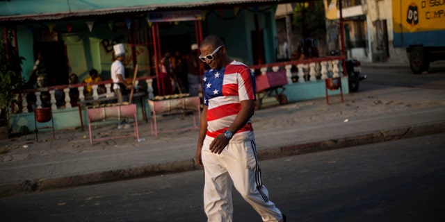 In this March 21, 2015 photo, a man wears a shirt with a U.S. flag design in Santiago, Cuba. Its easier to get from Havana to Miami than to the islands second-largest city, which has just two overbooked flights a day and trains that are achingly slow and unpredictable. (AP Photo/Ramon Espinosa)