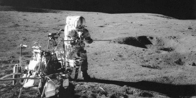 Apollo 14 astronaut Alan B. Shepard Jr. conducts an experiment near a lunar crater.