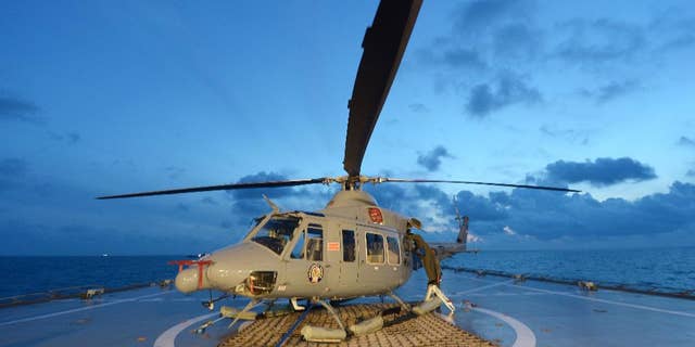 Indonesian navy personnel check a helicopter as they prepare operations to lift the tail of AirAsia Flight 8501 in Java sea, Indonesia Friday, Jan. 9, 2015. Days after sonar detected apparent wreckage, an unmanned underwater vehicle showed the plane's tail, lying upside down and partially buried in the ocean floor. (AP Photo/Adek Berry, Pool)