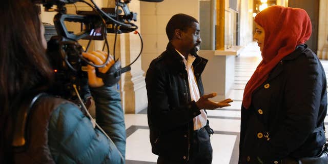 FILE - In this Feb.25, 2015 file photo, plaintiff Bocar, center, is interviewed by the media at the Paris appeals court in Paris, France. A French appeals court has ruled Wednesday June 24, 2015 that police carried out unjustified identity checks on five minority men, ordering the government to pay them damages in an unprecedented ruling that activists hope will help reduce widespread discrimination. (AP Photo/Francois Mori, File)