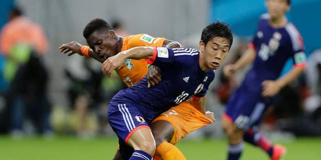 Japan's Shinji Kagawa, front, battles for the ball with Ivory Coast's Serge Aurier during the group C World Cup soccer match between Ivory Coast and Japan at the Arena Pernambuco in Recife, Brazil, Saturday, June 14, 2014. (AP Photo/Ricardo Mazalan)
