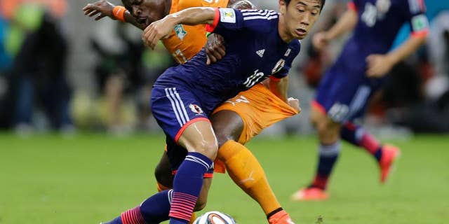 Japan's Shinji Kagawa, front, battles for the ball with Ivory Coast's Serge Aurier during the group C World Cup soccer match between Ivory Coast and Japan at the Arena Pernambuco in Recife, Brazil, Saturday, June 14, 2014. (AP Photo/Ricardo Mazalan)