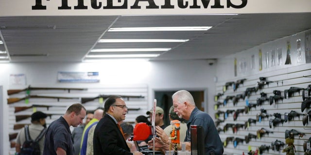 n this Dec. 9, 2015, file photo, sales associate Mike Conway, right, shows Paul Angulo a pistol at Bullseye Sport gun shop in Riverside, Calif. A U.S. judge has struck down a nearly century-old California law that banned gun shops from advertising handguns on their premises.