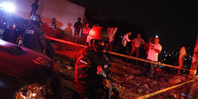 A military policeman stands guard after the old police headquarters building was raided by the Honduran Army and prosecution agents in Tegucigalpa, Honduras, late Monday, April 4, 2016. The agents were looking for evidence in the assassination of anti-drug prosecutor Julian Aristides Gonzalez in 2009. The Honduran government has vowed to suspend several top police officials amid mounting evidence they conspired to kill Gonzalez and two other prosecution employees. (AP Photo/Fernando Antonio)