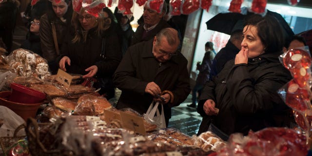 In this Monday Feb. 3, 2014 photo, people look at a stand, at a street market, in Pamplona, northern Spain. The Spanish government figures show that number of people registered as unemployed rose by 113,097 in January as temporary job contracts created over Christmas came to an end. (AP Photo/Alvaro Barrientos)