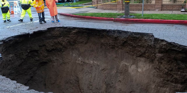 Inspectors examine a sinkhole Saturday, Feb. 18, 2017, in Studio City, north of Los Angeles. Two vehicles fell into the 20-foot sinkhole on Friday night and firefighters had to rescue one woman who escaped her car but was found standing on her overturned vehicle. (AP Photo/Ringo H.W. Chiu)