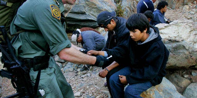 Border patrol agent Jeff Mielke secures plastic handcuffs on a group of undocumented immigrants caught in the Otay Mesa Mountain Range, just east of San Diego.