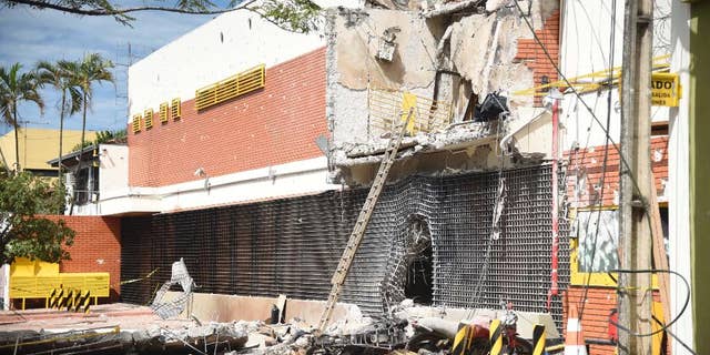 The partly demolished building of the armored car company Prosegur is seen after assailants blew it up, in Ciudad del Este, Paraguay, Monday, April 24, 2017. A gang of over 50 armed bandits stole several million dollars from a vault in the company, in what local officials are dubbing the "robbery of the century". The culprits, who police said were from Brazil, killed one police officer during the Monday raid. (Roberto Zarza/Diario ABC Color via AP)