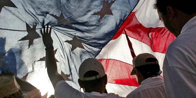 Immigration rights demonstrators hold a U.S. flag aloft during a march along Wilshire Boulevard, Monday, May 1, 2006, in Los Angeles. (AP Photo/Stefano Paltera)