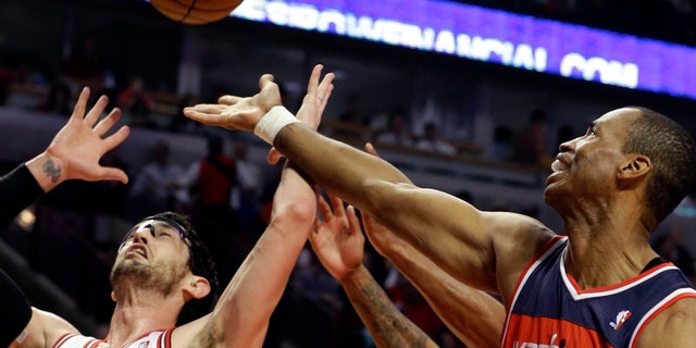 FILE - In this April 17, 2013 file photo, Washington Wizards center Jason Collins, right, battles for a rebound against Chicago Bulls guard Kirk Hinrich during the first half of an NBA basketball game in Chicago. Jason Collins has become the first male professional athlete in the major four American sports leagues to come out as gay. Collins wrote a first-person account posted Monday on Sports Illustrated's website. The 34-year-old Collins has played for six NBA teams in 12 seasons. He finished this past season with the Washington Wizards and is now a free agent. He says he wants to continue playing. (AP Photo/Nam Y. Huh, File)