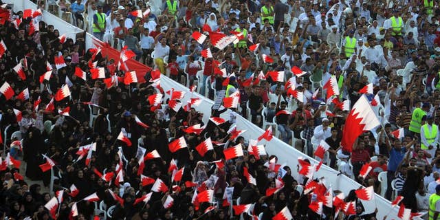 FILE- In this Friday, Sept. 30, 2011 file photo, Bahraini anti-government protesters wave flags and chant during a rally of thousands organized by Al-Wefaq, the largest Shiite opposition party, to demand greater freedoms in Quraya, Bahrain. Bahrain has again allowed agents of its domestic spy service to make arrests, reversing a key reform recommended in the wake of the crackdown that followed its 2011 Arab Spring protests. (AP Photo/Hasan Jamali, File)