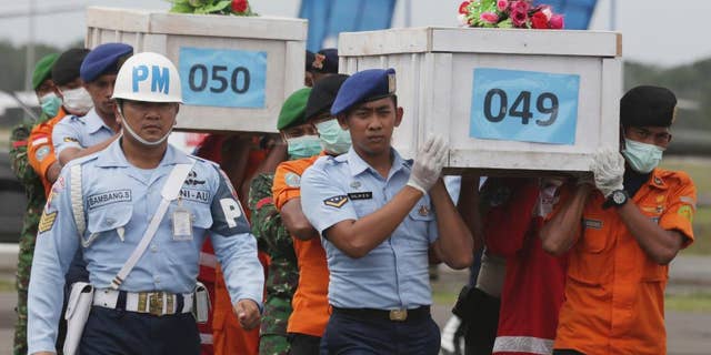 FILE - In this Monday, Jan. 19, 2015, file photo, members of the National Search and Rescue Agency carry coffins containing bodies of the victims aboard AirAsia Flight 8501 to transfer to Surabaya at the airport in Pangkalan Bun. The plane was climbing at an abnormally high rate, then plunged and suddenly disappeared from radar, Indonesia's transport minister said Tuesday, Jan. 20. (AP Photo/Achmad Ibrahim, File)