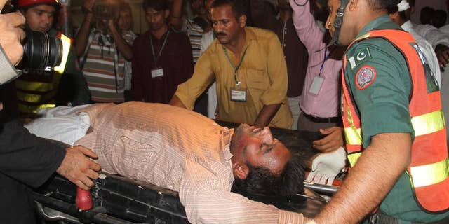 Pakistani rescue workers rush an injured person to a local hospital in Multan, Pakistan, Friday, Oct. 10, 2014. A stampede at a political rally of Pakistan's former cricketer turned politician, Imran Khan, left some scores of people dead and dozens more injured, police said. (AP Photo/Asim Tanveer)