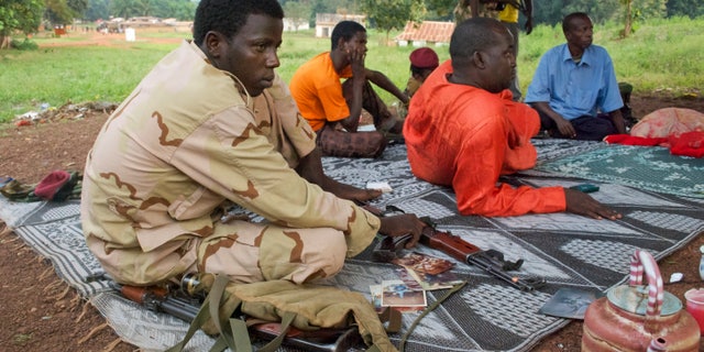 In this photo taken Monday, Nov. 25, 2013, armed Muslim fighters from the former Seleka rebel coalition sit in the town of Bouca in the Central African Republic. France's foreign minister has warned that its former colony in central Africa is "on the verge of genocide" as attacks mount across the country's remote northwest between the mostly Muslim fighters of the Seleka rebel coalition who ousted the president in March, and "anti-balaka" Christian militias that have emerged to defend towns and in some cases attack Muslim civilian communities. (AP Photo/Florence Richard)
