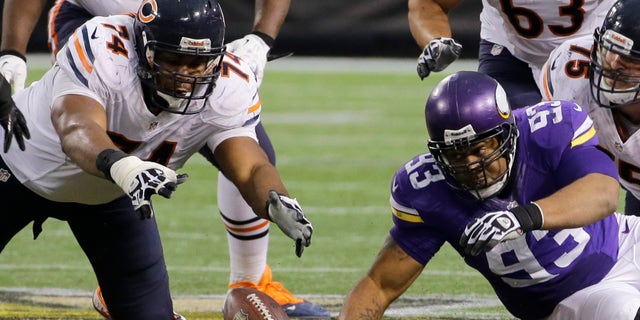 Chicago Bears tackle Jermon Bushrod, left, and Minnesota Vikings defensive tackle Kevin Williams, right, eye a fumble during the fourth quarter of an NFL football game on Sunday, Dec. 1, 2013, in Minneapolis. The Vikings won 23-20 in overtime. (AP Photo/Ann Heisenfelt)