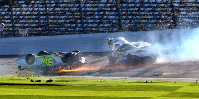 Parker Kligerman (30) slides upside down through the front stretch as Dave Blaney (77) goes around after a crash during a practice session for the NASCAR Daytona 500 auto race at Daytona International Speedway in Daytona Beach, Fla., Wednesday, Feb. 19, 2014. (AP Photo/Alex Menendez)