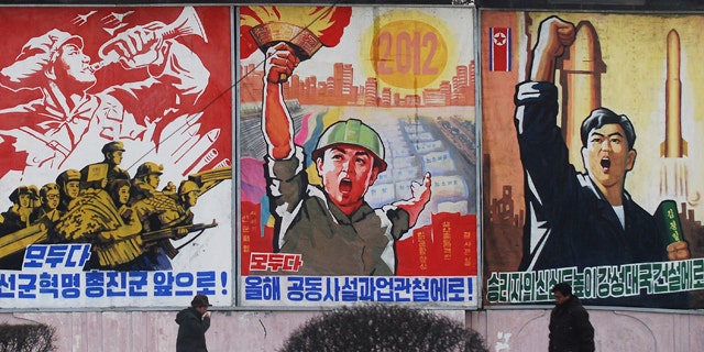 In this Feb. 11, 2012 photo, residents walk past posters with popular slogans illustrating North Korea's main policies, on a street in Pyongyang, North Korea. From left to right, they read "Let's march toward a military first revolution," "Let's accomplish the tasks laid out in this year's joint new year's editorial,' and "Devote the victors' hearts to the building of a strong nation."