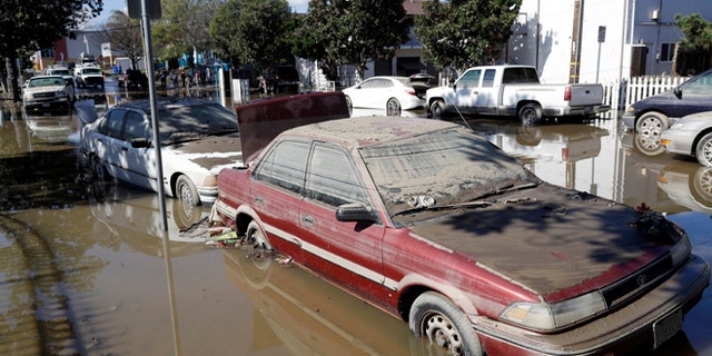 FILE - In this Feb. 23, 2017, file photo, cars are partially submerged and covered in mud from receding floodwaters in San Jose, Calif. California billionaire Kieu Hoang donated $5 million to flood relief efforts on March 1, 2017. (AP Photo/Marcio Jose Sanchez, File)