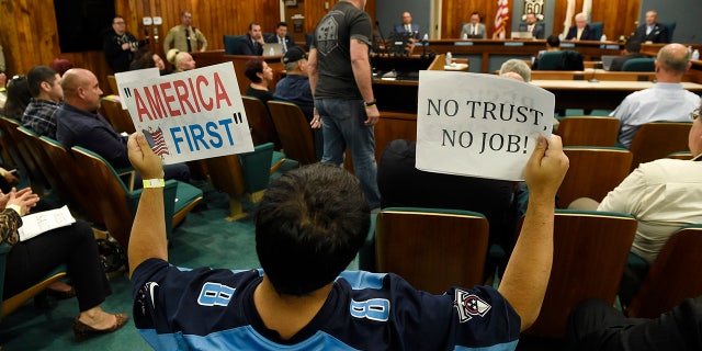 Jamie Park of Pico Rivera, Calif., holds up signs during a city council meeting at Pico Rivera City Hall on Tuesday.