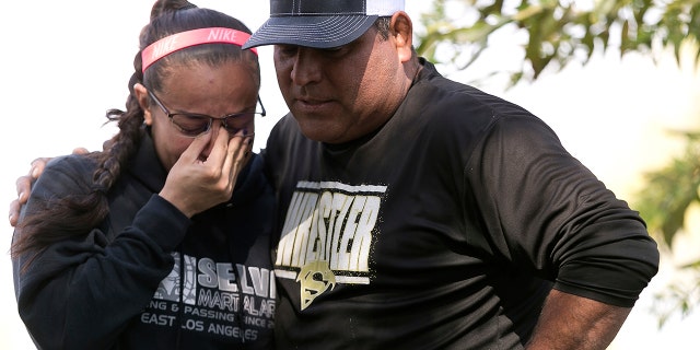 Wrestling coach Ray Castellanos, right, and assistant coach, Monique Cabrera, left, stand at the site where South El Monte High School student, Jeremy Sanchez, a 17-year-old was fatally stabbed by a teenage friend, in South El Monte, Calif.