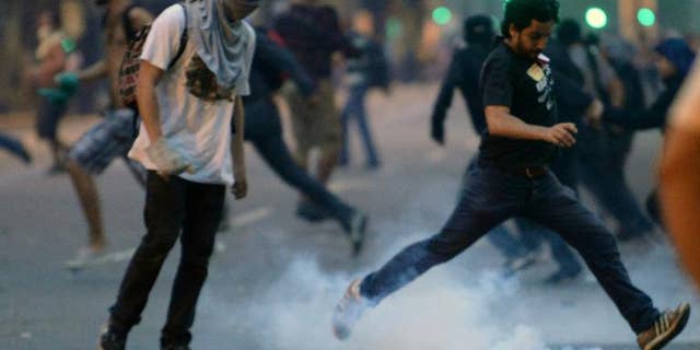 A demonstrator kicks a tear gas grenade during a protest by teachers in Rio de Janeiro, Brazil, on October 1, 2013