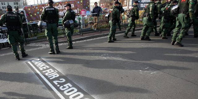 In this picture taken Saturday, Nov. 15, 2014, police stand in front of banners reading "Donate with every step, march", top left, and "#right against right" top right, during a far-right march Wunsiedel, southern Germany. Letters on the ground say "Thanks for euro 2,500!". After failing to prevent neo-Nazis from staging an annual pilgrimage to the birthplace of Adolf Hitler’s deputy Rudolf Hess, the Bavarian town decided to change tack this year. Residents and businesses pledged to pay 10 euro (US dollar 12.50) for every meter the neo-Nazis walked, and motivational signs were erected along the route of Saturday’s march. Inge Schuster, a spokeswoman for the town, said Tuesday that the stunt received “a great response,” raising more than 10,000 euros for the group EXIT-Deutschland that helps people leave the neo-Nazi scene. (AP Photo/dpa, Fricke)