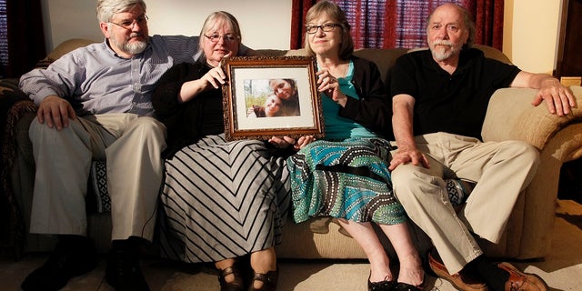 Patrick Boyle, Linda Boyle, Lyn Coleman and Jim Coleman holding a photo of their kidnapped children, Joshua Boyle and Caitlan Coleman, in 2014.