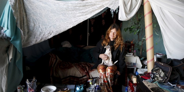 Karen Souza, 55, poses for a portrait with her dog Handsome by the tent in which she lives, under a freeway on a street in Los Angeles.