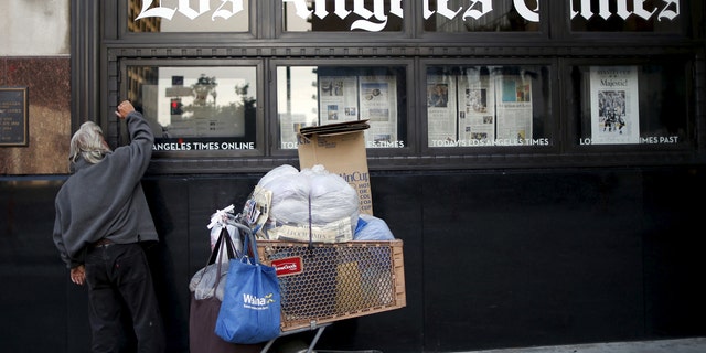A homeless man reads the Los Angeles Times in the window of the building of Los Angeles Times newspaper in Los Angeles.