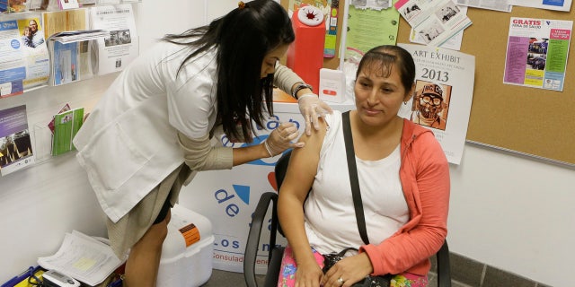 In this Oct. 1, 2013, file photo, Walgreens' pharmacist, Jennifer de Jesus, left, administers a free influenza vaccine to Ana Navarro, 33, during the Binational Health Week event held at the Mexican Consulate in Los Angeles.
