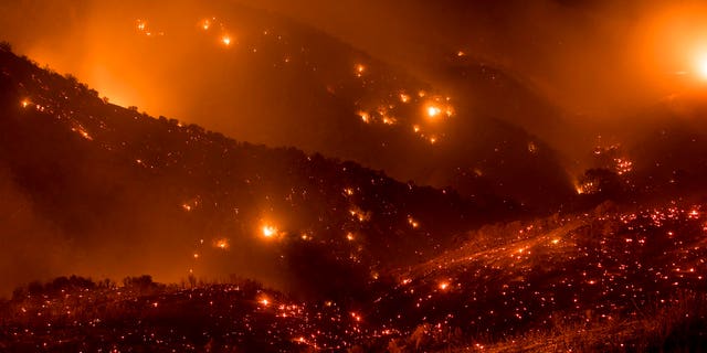 A hillside glows with embers as the Thomas fire burns through Los Padres National Forest near Ojai, Calif.