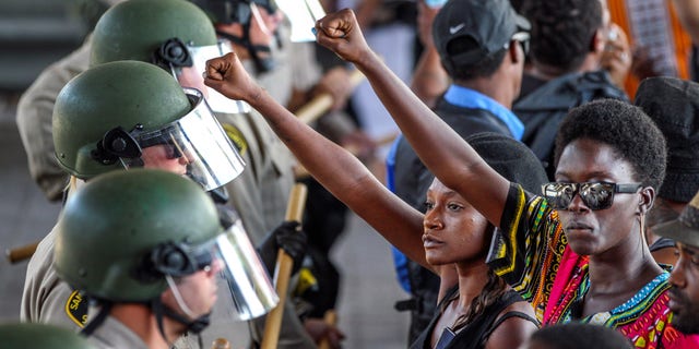 Ebonay Lee, center, and another unidentified woman hold up their fists during a demonstration in front of police on Sept. 28. in El Cajon, Calif.