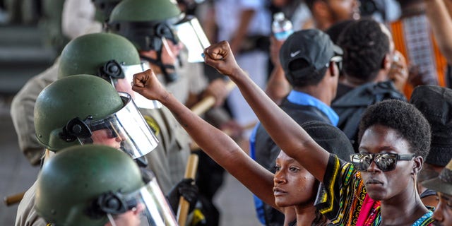 Ebonay Lee, center, and another unidentified woman hold up their fists during a demonstration in front of police on Sept. 28. in El Cajon, Calif.