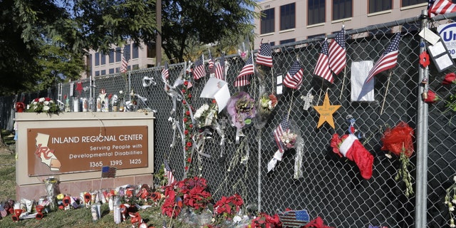 Photos, flowers and American flags honoring the victims of the San Bernardino terror attack hang outside the Inland Regional Center where the fatal shooting took place.