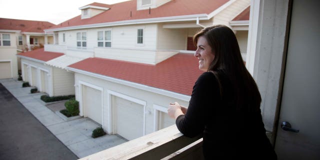 In this Dec. 11, 2015, photo, Katy Howser, a kindergarten teacher in the Santa Clara School District, looks out from the balcony of her apartment at Casa Del Maestro, an apartment complex for teachers, in Santa Clara, Calif. School districts in high cost-of-living areas and rural communities that have long struggled to staff classrooms are considering buying or building rent-subsidized apartments as a way to attract and retain teachers amid concerns of a looming shortage. (AP Photo/Marcio Jose Sanchez)