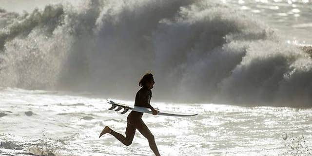 A surfer runs into the ocean at Seal Beach, Calif. on Thursday.