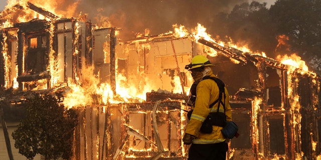 A firefighter monitors a house burning in Santa Rosa, Calif., Monday, Oct. 9, 2017.