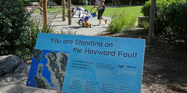 In this Tuesday, Oct. 18, 2016 photo, a sign notifying people they are standing on the Hayward Fault stands at the children's zoo area at the Oakland Zoo in Oakland, Calif.