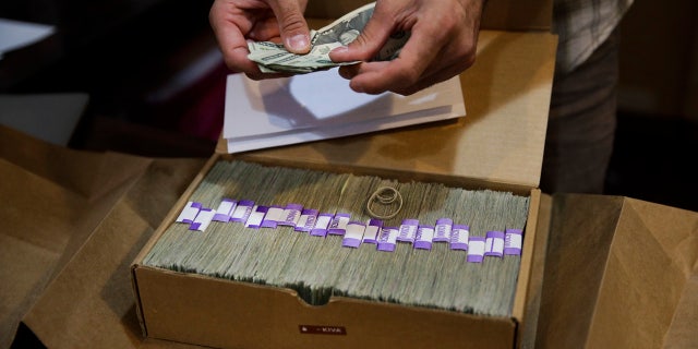 In this June 27, 2017, file photo, Jerred Kiloh, owner of the Higher Path medical marijuana dispensary, prepares his monthly tax payment, $40,131.88 in cash in Los Angeles.