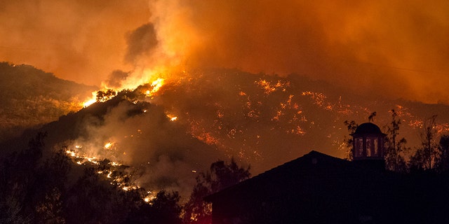The fifth largest wildfire in California history expanded, ripping through dry brush atop a coastal ridge while crews struggled to keep flames from roaring down into neighborhoods amid fears of renewed winds.