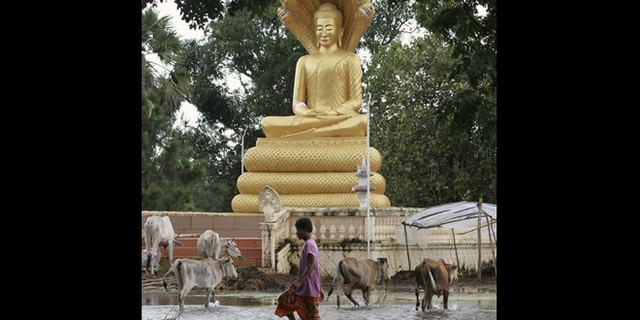Oct. 13, 2011: A boy walks in flood waters past a Buddha statue in Kampong Thom province.