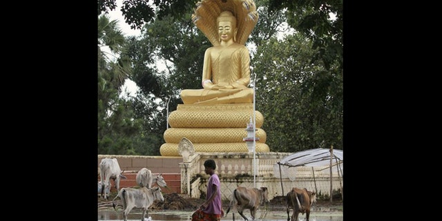 Oct. 13, 2011: A boy walks in flood waters past a Buddha statue in Kampong Thom province.