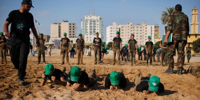 Palestinian boys crawl during a military-style exercise at a summer camp organized by the Hamas movement in Gaza City June 17, 2013. Tens of thousands of children from the Gaza Strip spend at least part of their holidays in special summer camps, arranged around a wide array of activities. Some, organised by the United Nations, offer sports, art and dance classes. Others, laid on by Gaza's Islamist rulers Hamas, include fun and games, while seeking to reinforce religious values and awareness of the conflict with Israel. Picture taken June 17, 2013. REUTERS/Mohammed Salem (GAZA - Tags: POLITICS EDUCATION SOCIETY)
ATTENTION EDITORS: PICTURE 09 OF 31 FOR PACKAGE 'ON HOLIDAY IN GAZA'S SUMMER CAMPS'. TO FIND ALL IMAGES SEARCH 'SUMMER CAMPS' - RTX10ZZQ