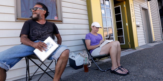 July 7, 2014: George Vargas, left, takes a seat next to first-in-line customer Deb Greene in front of the recreational marijuana store Cannabis City in Seattle. The store will be the first and only store initially in Seattle to legally sell recreational pot when sales begin Tuesday.