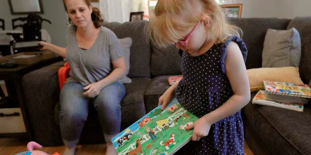 In this Monday, July 23, 2018, photo minutes before having a seizure, Brooke Adams, 5, plays with her toys with her mother, Jana at their home in Santa Rosa, Calif.