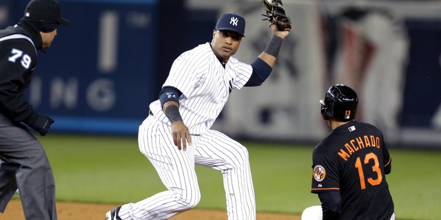 New York Yankees second baseman Robinson Cano, center, waits for the call from second base umpire Manny Gonzalez, left, after tagging Baltimore Orioles' Manny Machado for the third out of a triple play during the eight inning of a baseball game at Yankee Stadium in New York, Friday, April 12, 2013. (AP Photo/Julio Cortez)