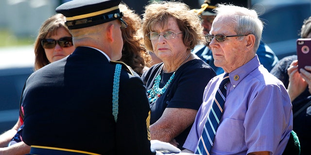 Wayne Brazeau, right, next to his wife Dorothy Brazeau, is handed the flag by 1st Sgt. Raymond Wrensch, left, during the burial service at Arlington National Cemetery on Tuesday in Arlington, Va., for Army Air Force Staff Sgt. John H. Canty.